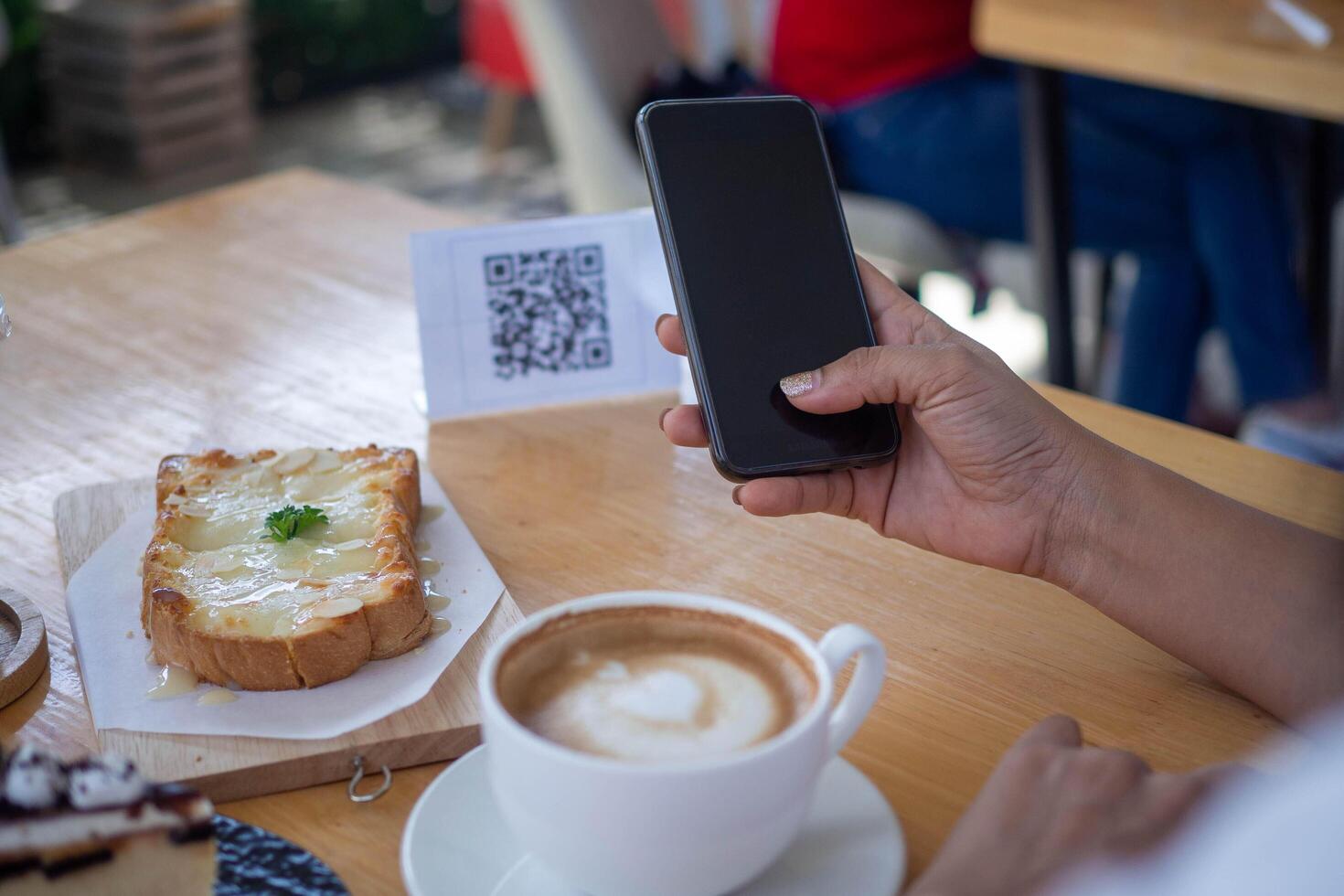 Woman use smartphone to scan QR code to pay in cafe restaurant with a digital payment without cash. Choose menu and order accumulate discount. E wallet, technology, pay online, credit card, bank app. photo