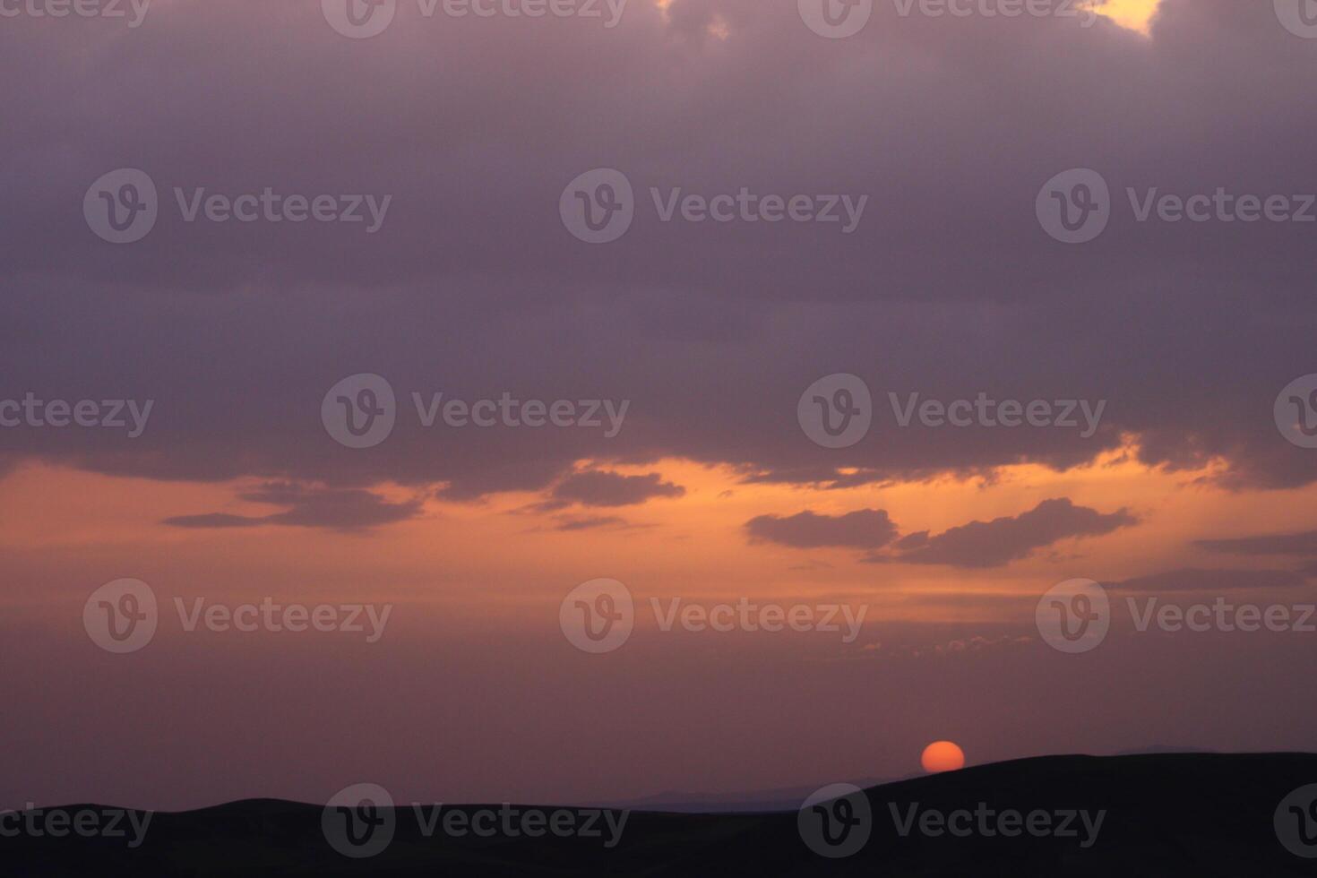 a sunset with clouds and a orange sun setting in the sky. photo