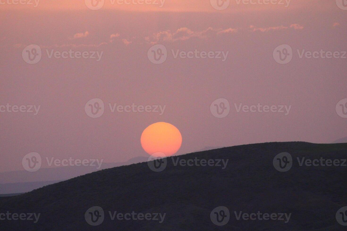 a sunset with clouds and a orange sun setting in the sky. photo