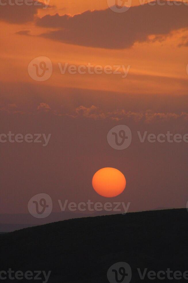 a sunset with clouds and a orange sun setting in the sky. photo