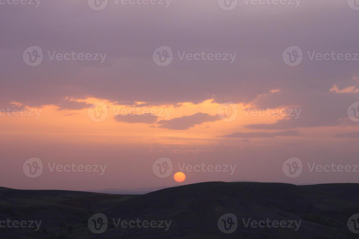 a sunset with clouds and a orange sun setting in the sky. photo