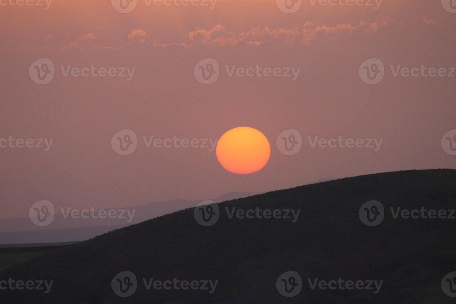 a sunset with clouds and a orange sun setting in the sky. photo