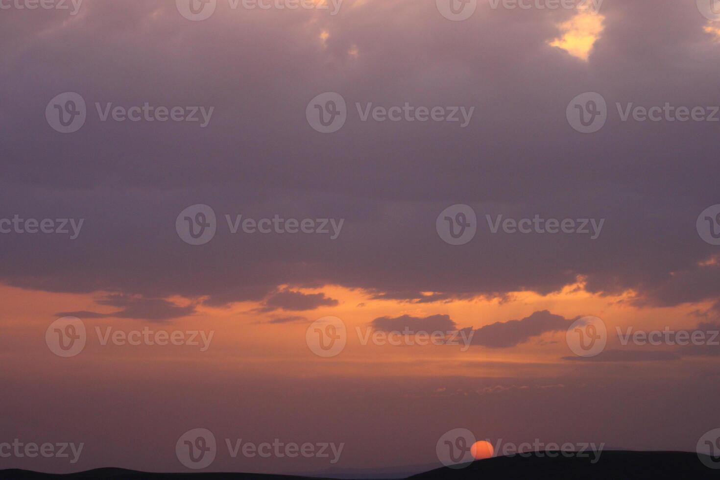 a sunset with clouds and a orange sun setting in the sky. photo