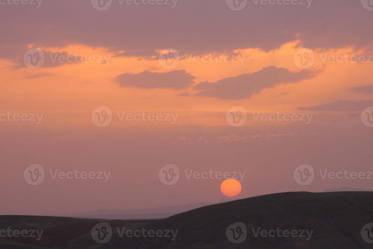 a sunset with clouds and a orange sun setting in the sky. photo