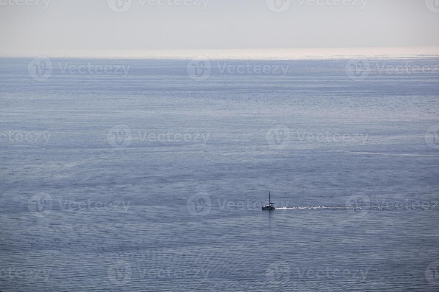A small sailing boat sails on the sea surface of the Adriatic Sea. Balkans. View from above. Montenegro. Budva. Horizontal. photo