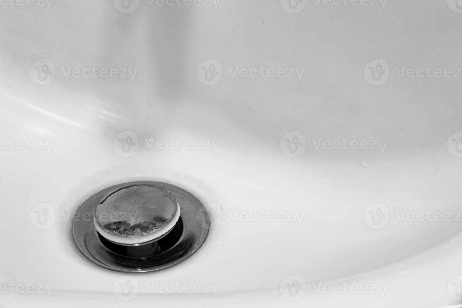 Detail of a ceramic white sink in a modern bathroom with chrome plated drain. Horizontal. For text. photo