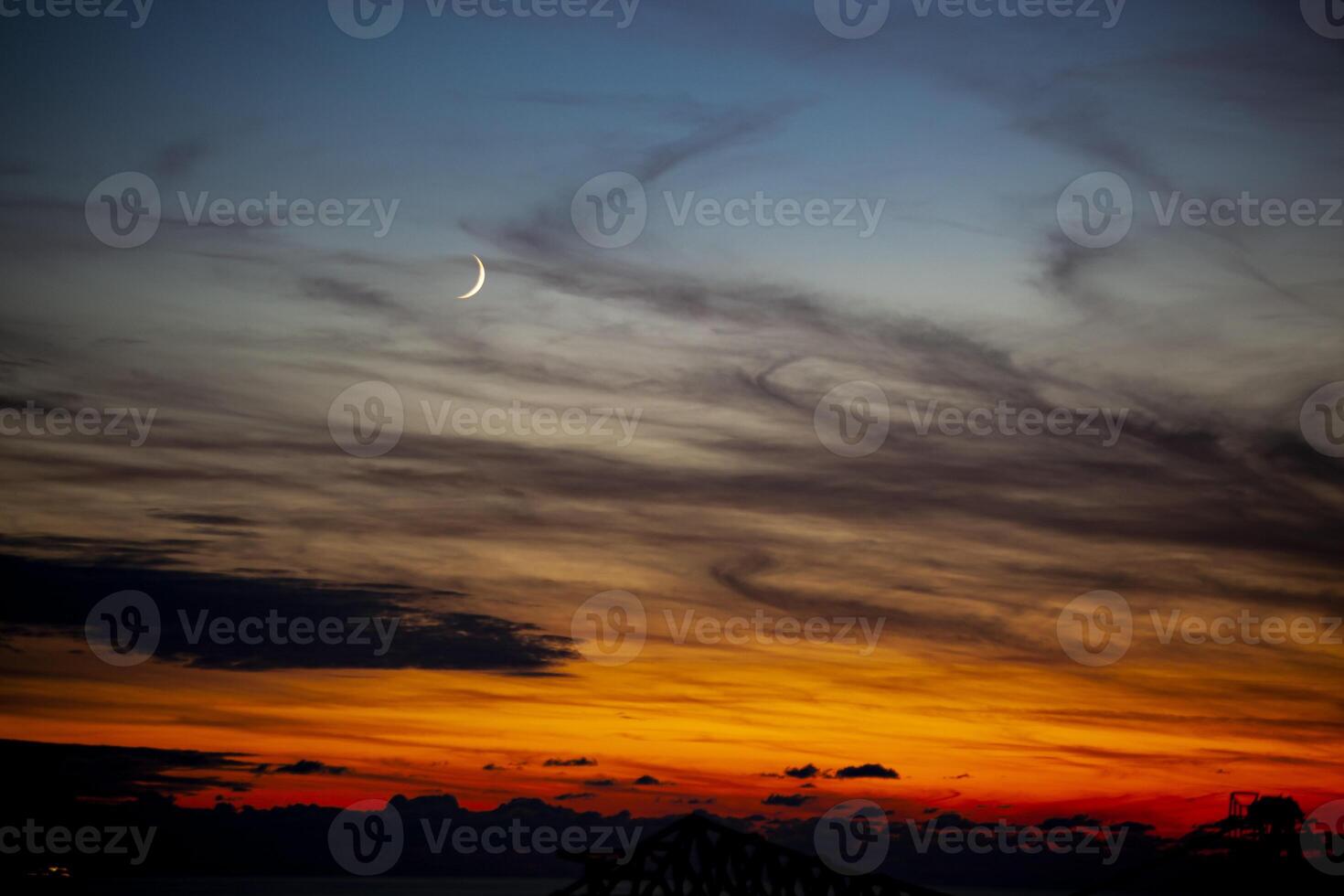 Red-orange sky at sunset in twilight evening with dark clouds and moon. Nature sky. Background, horizon golden sky, sunrise cloud magnificent, twilight sky. photo