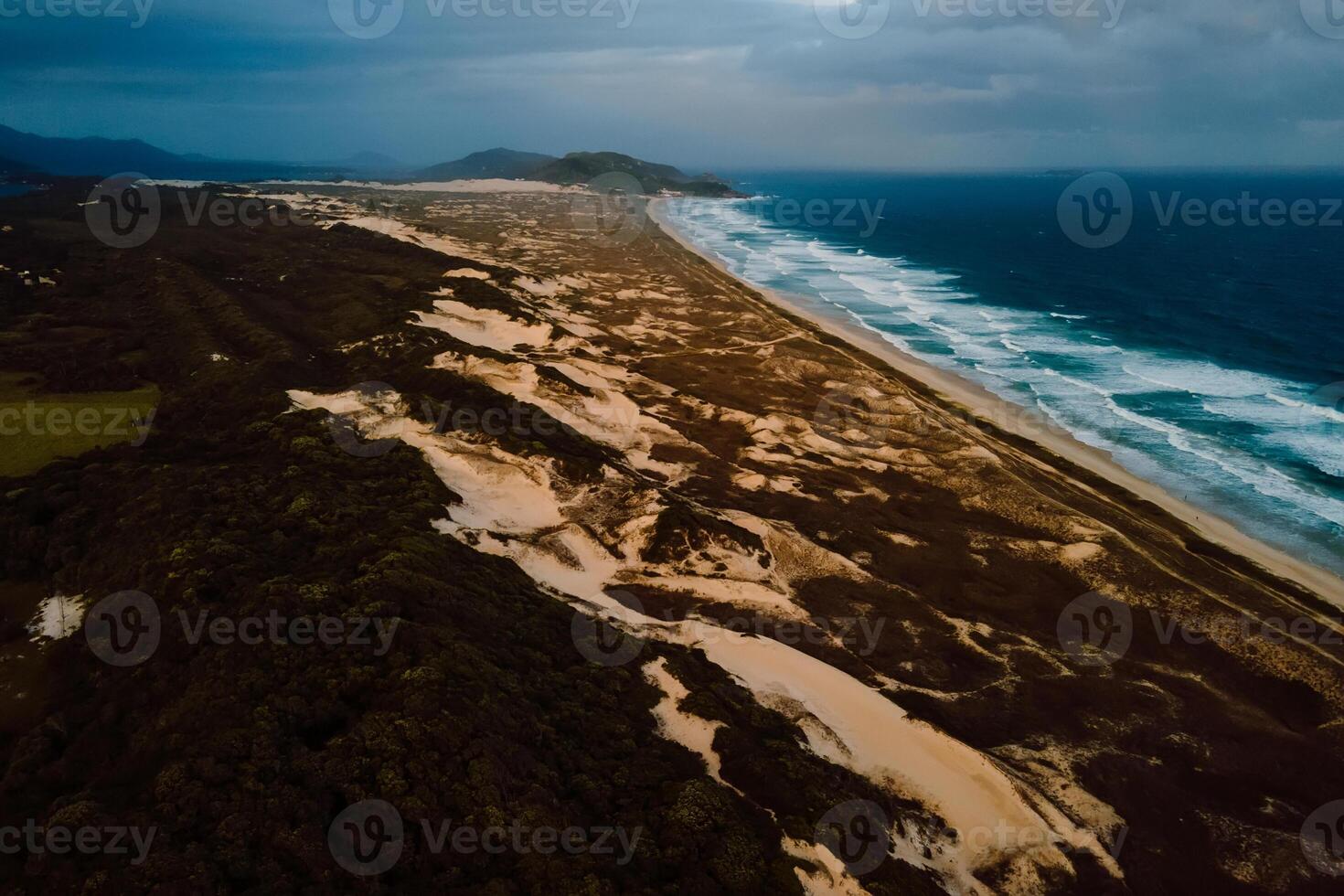 Beach with dunes and ocean waves with sunset tones in Florianopolis photo