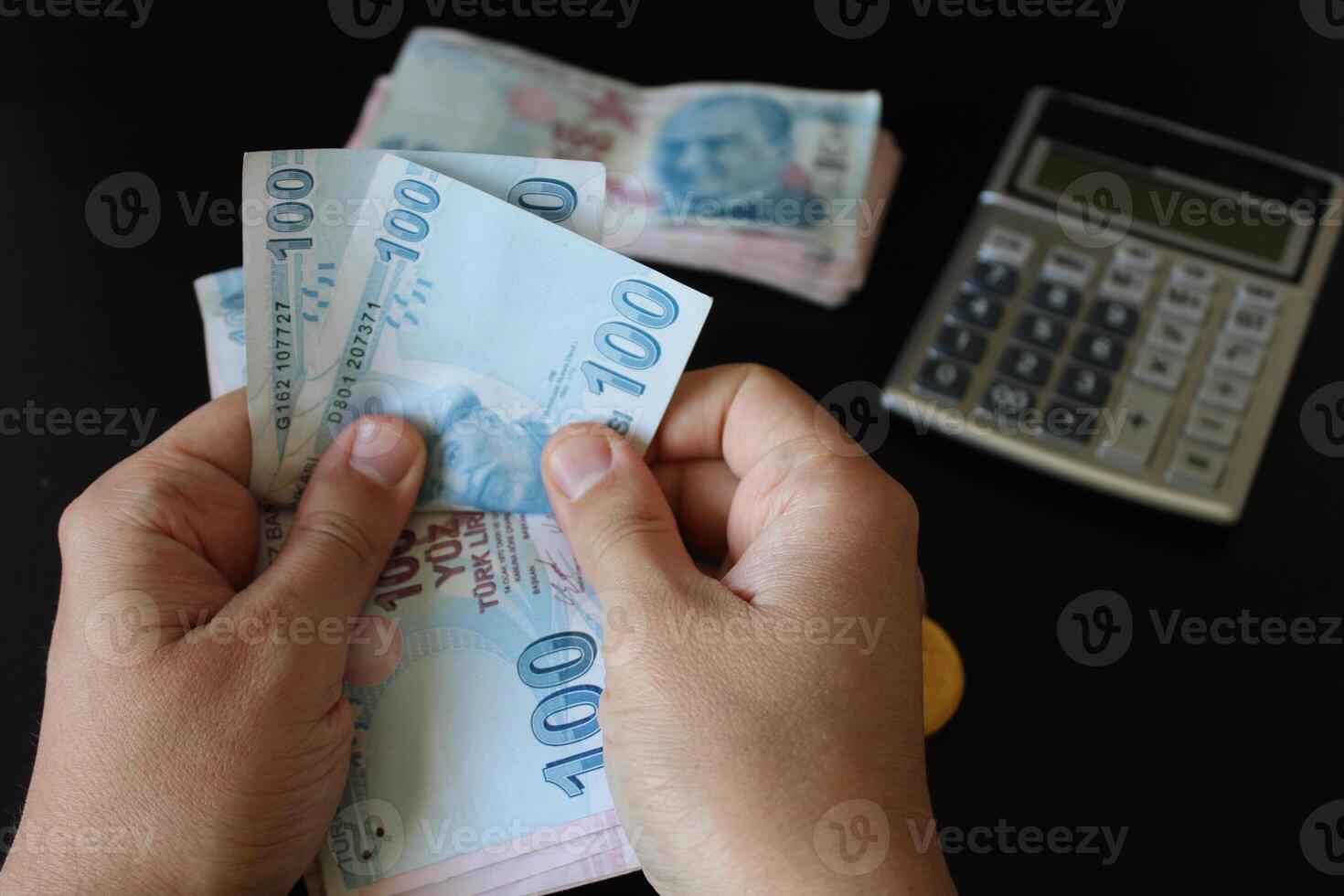 Turkish 100 lira banknotes.man counting Turkish money with his hand.Calculator in the background. The paper currency of Turkey. photo