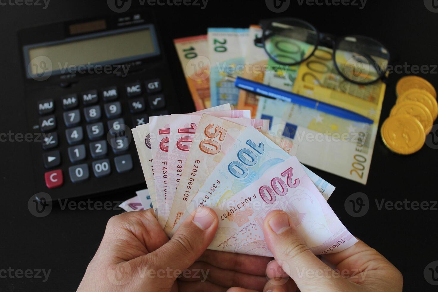 The paper currency of Turkey. Calculator in the background.Turkish lira banknotes. man counting Turkish money with his hand. photo