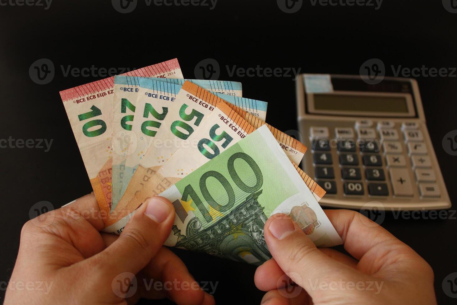 man counting euro money with his hand. euro banknotes. The paper currency of europan union .Calculator in the background. photo