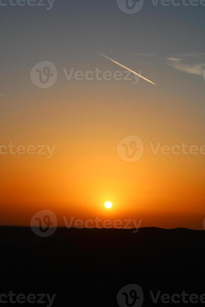 airplane and its trail in the sky. clouds and different color tones in the sky at sunset. Amazing and incredible sunset. photo