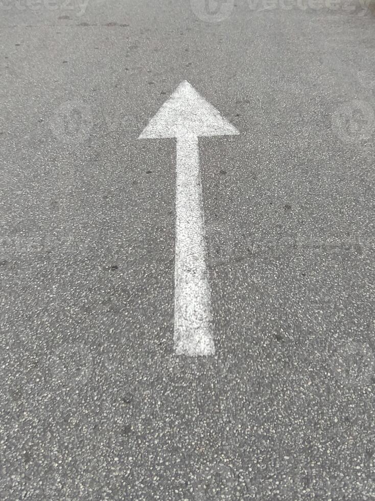White arrow painted on urban street asphalt. Indicating direction. photo