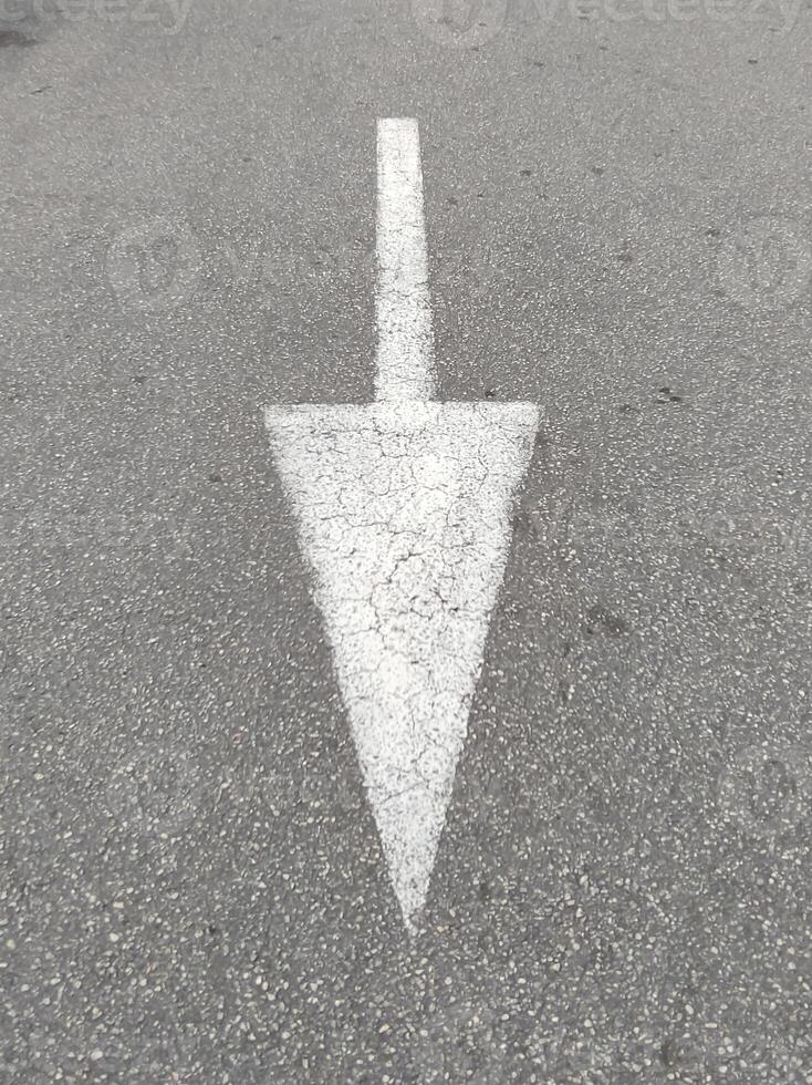 White arrow painted on urban street asphalt. Indicating direction. photo