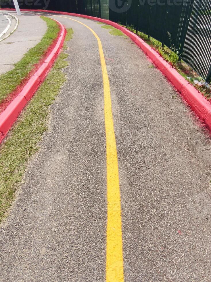 Deserted asphalt cycle path. Demarcated in red and yellow with a curve in perspective on a sunny day. photo