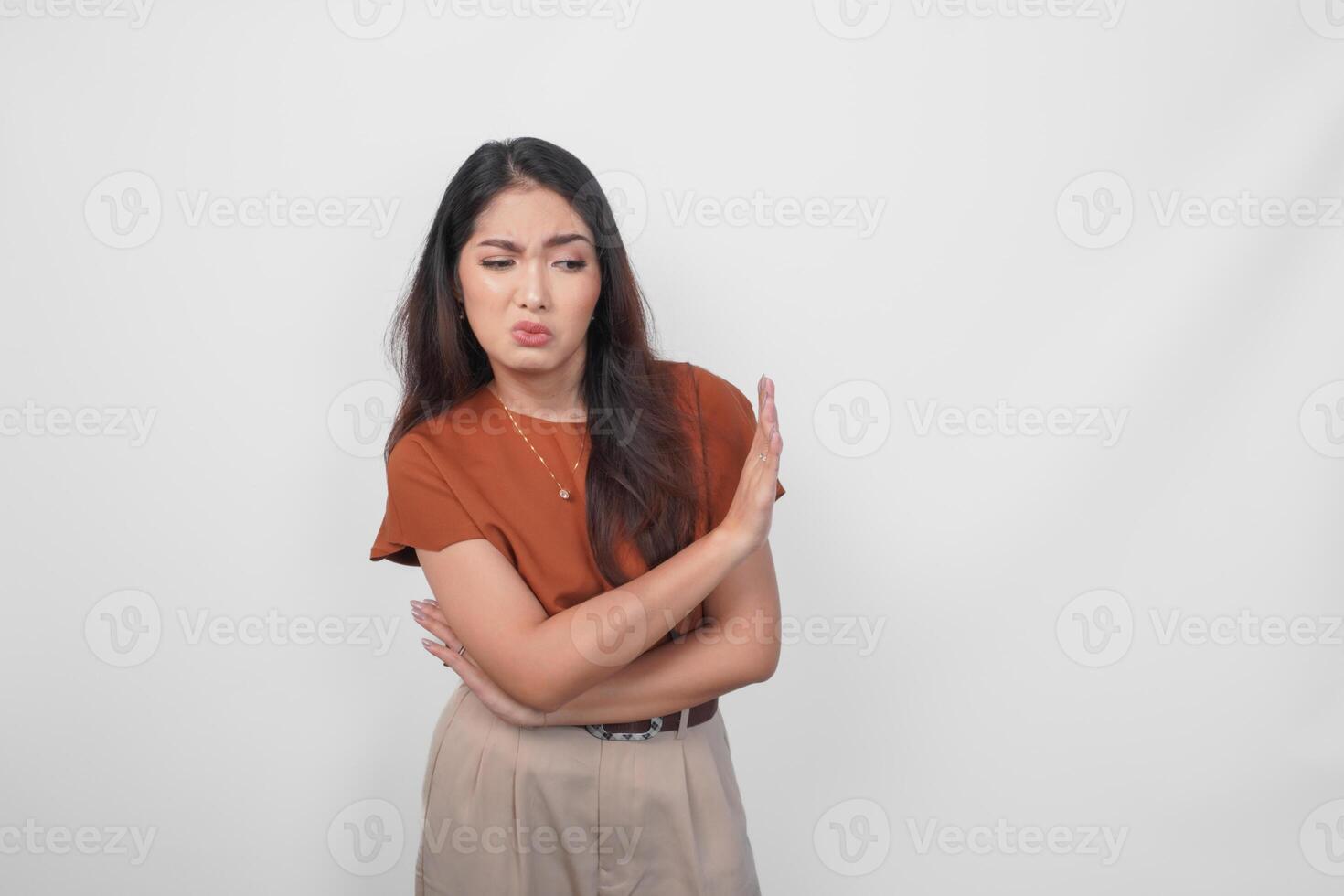 Upset young Asian woman wearing brown shirt doing stop sign with palm of the hand over white isolated background. photo