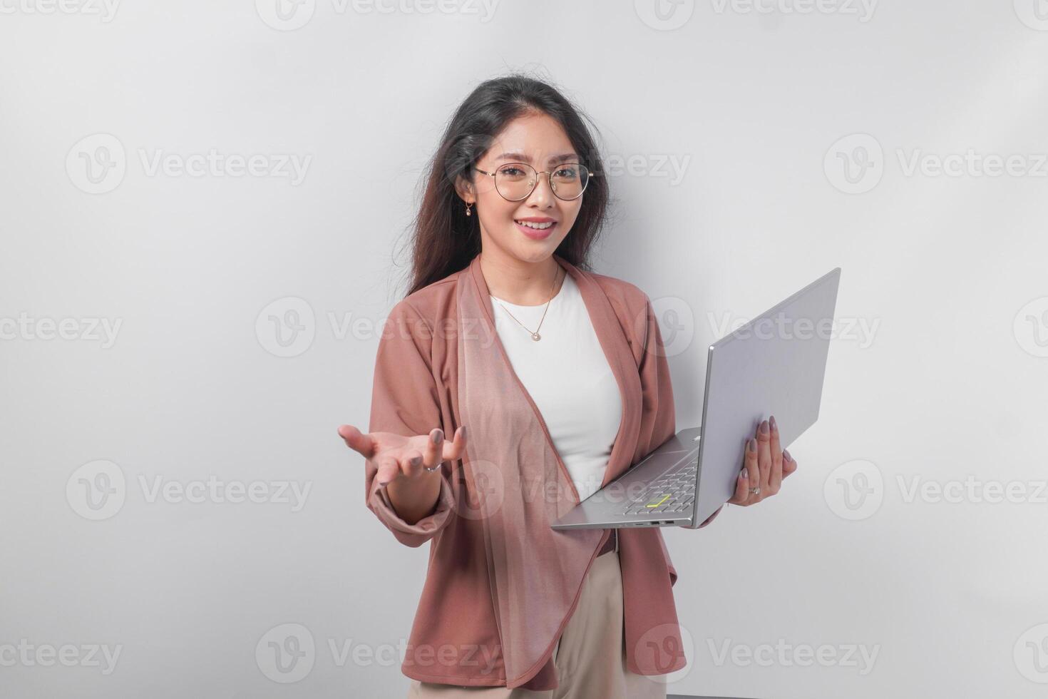 Elegant Asian business woman raising hand making inviting or lets go gesture while holding laptop, isolated over white background. photo