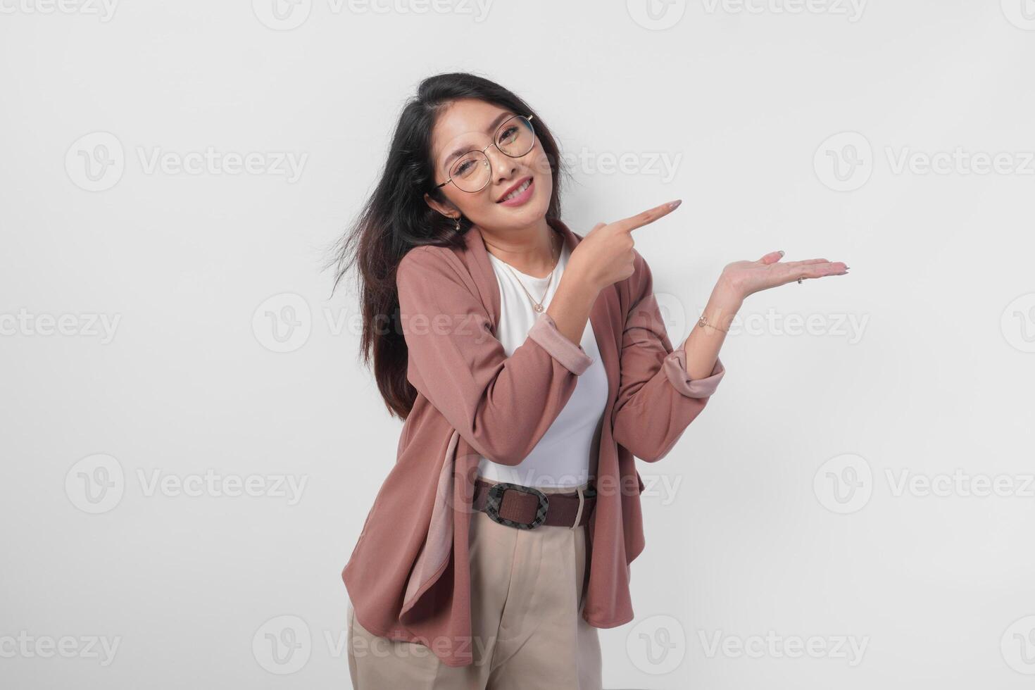 Smiling Asian woman presenting and pointing to the copy space beside her over isolated white background. photo