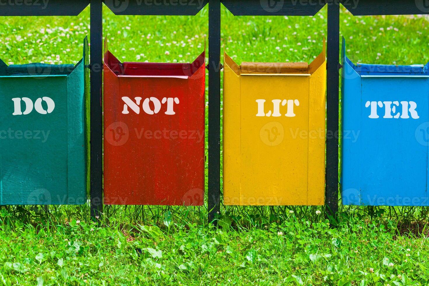 Four colors trash can in the park with inscription - do not litter photo