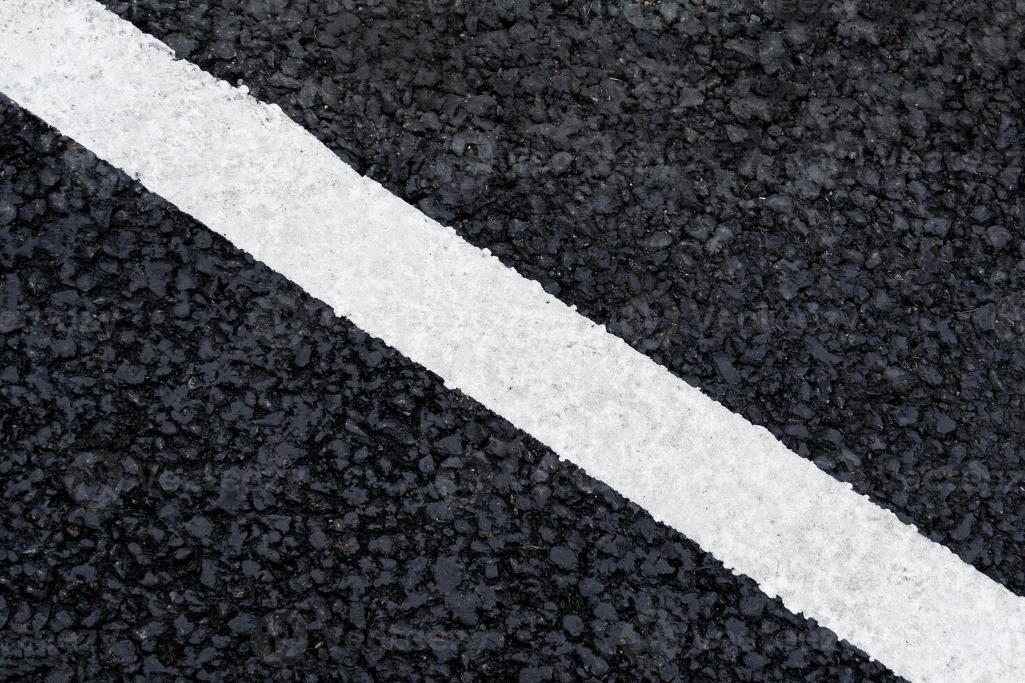 White diagonal marking line on the asphalt road as background, texture, abstract photo