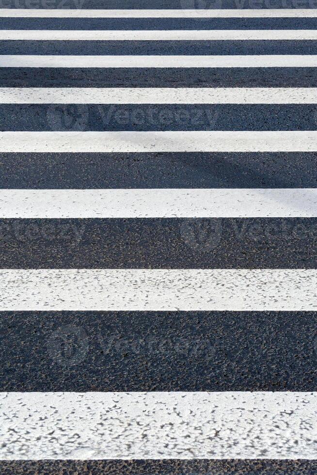 View of white markings pedestrian lines on a asphalt road as background, texture photo