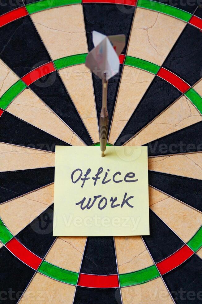 Dart hit the centre of target and attaches sticker with inscriptions - office work, concept photo