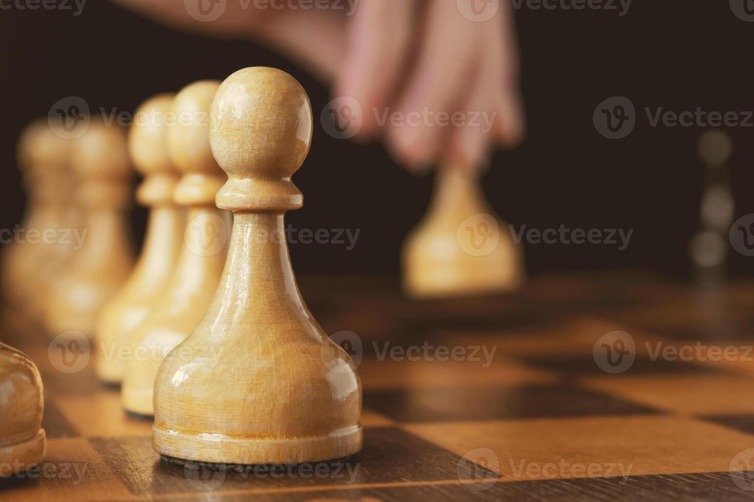A hand's of chess player makes a move the white pawn forward, out of focus, pawn on the foreground in focus photo