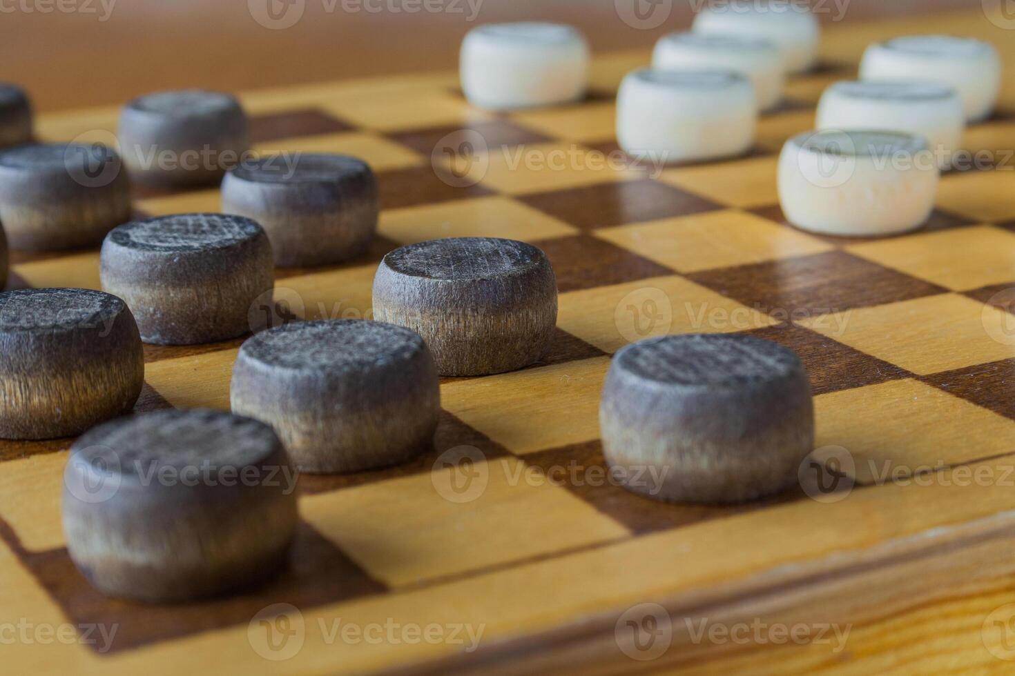 wooden checkerboard with checkers spaced on table photo