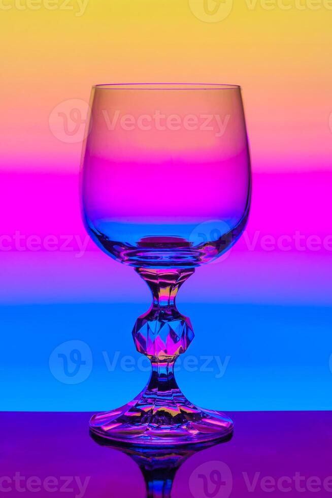 Crystal wine glass on a background of multi colored gradient photo