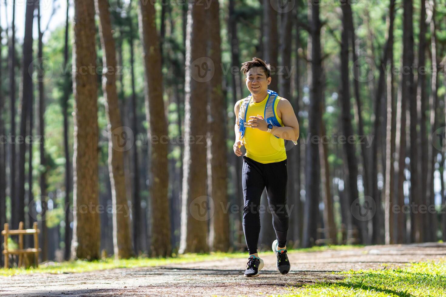 Asian trail runner is running outdoor in the pine forest dirt road with water backpack for exercise activities training to race in the ultra marathon to achieve healthy lifestyle and fitness photo