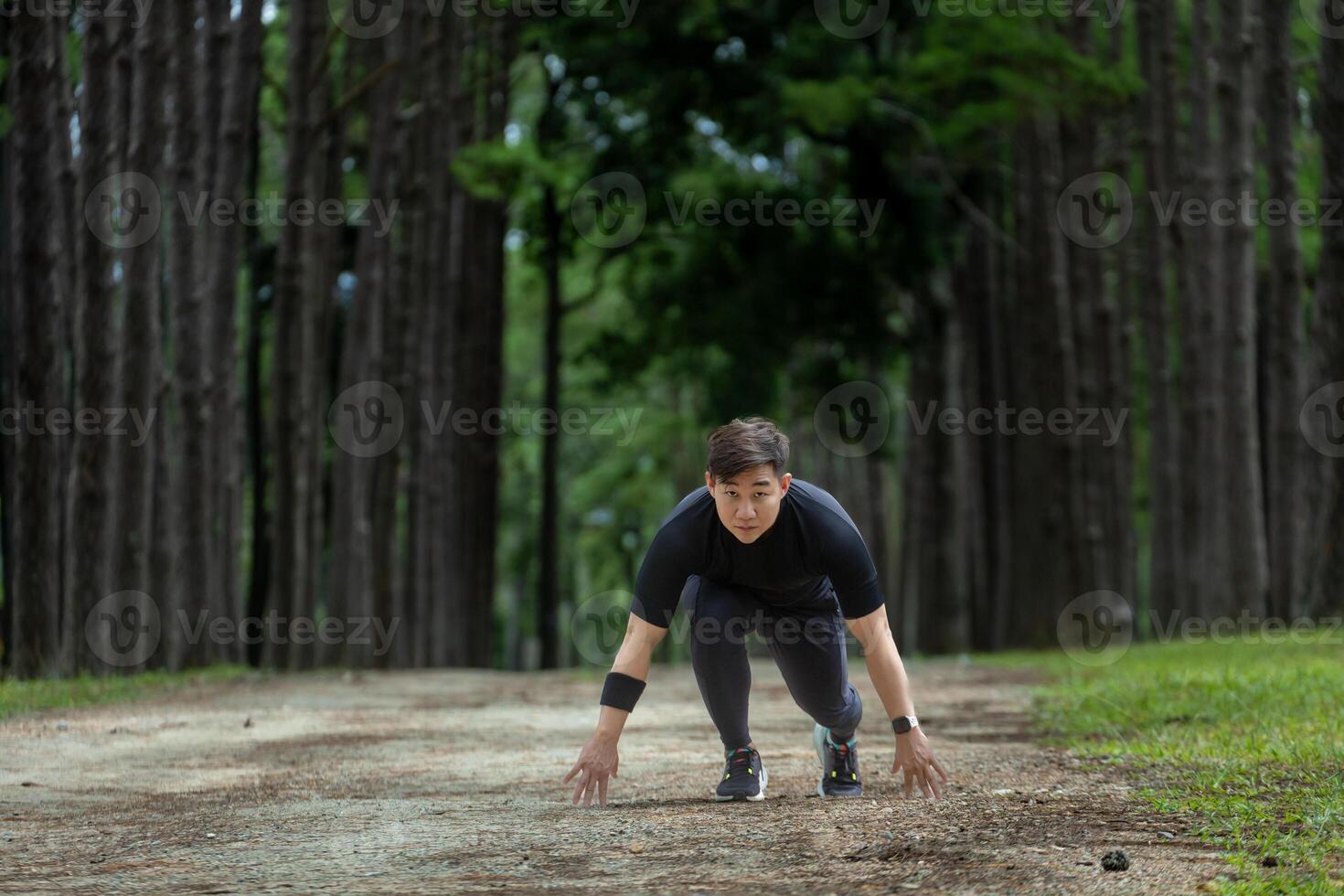 Asian trail runner is running outdoor in pine forest dirt road for exercise and workout activities training while concentrate on the start position to race for healthy lifestyle and fitness concept photo