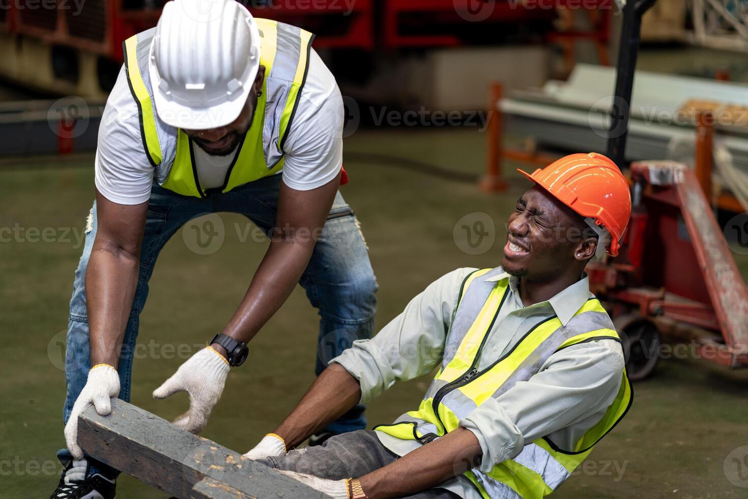African American factory worker having an accident while working in manufacturing site while his colleague is helping for safety workplace and emergency photo