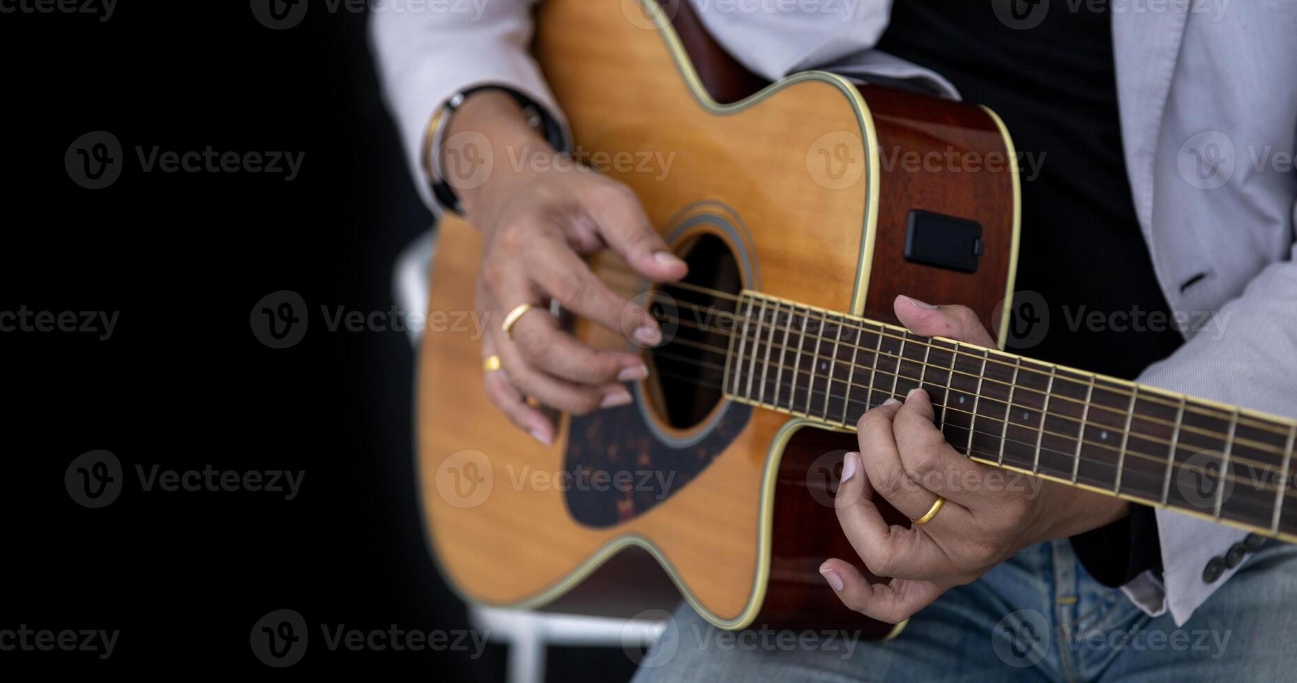Close up shot of guitarist playing acoustic guitar on black background with copy space for folk music and unplugged performance concept photo