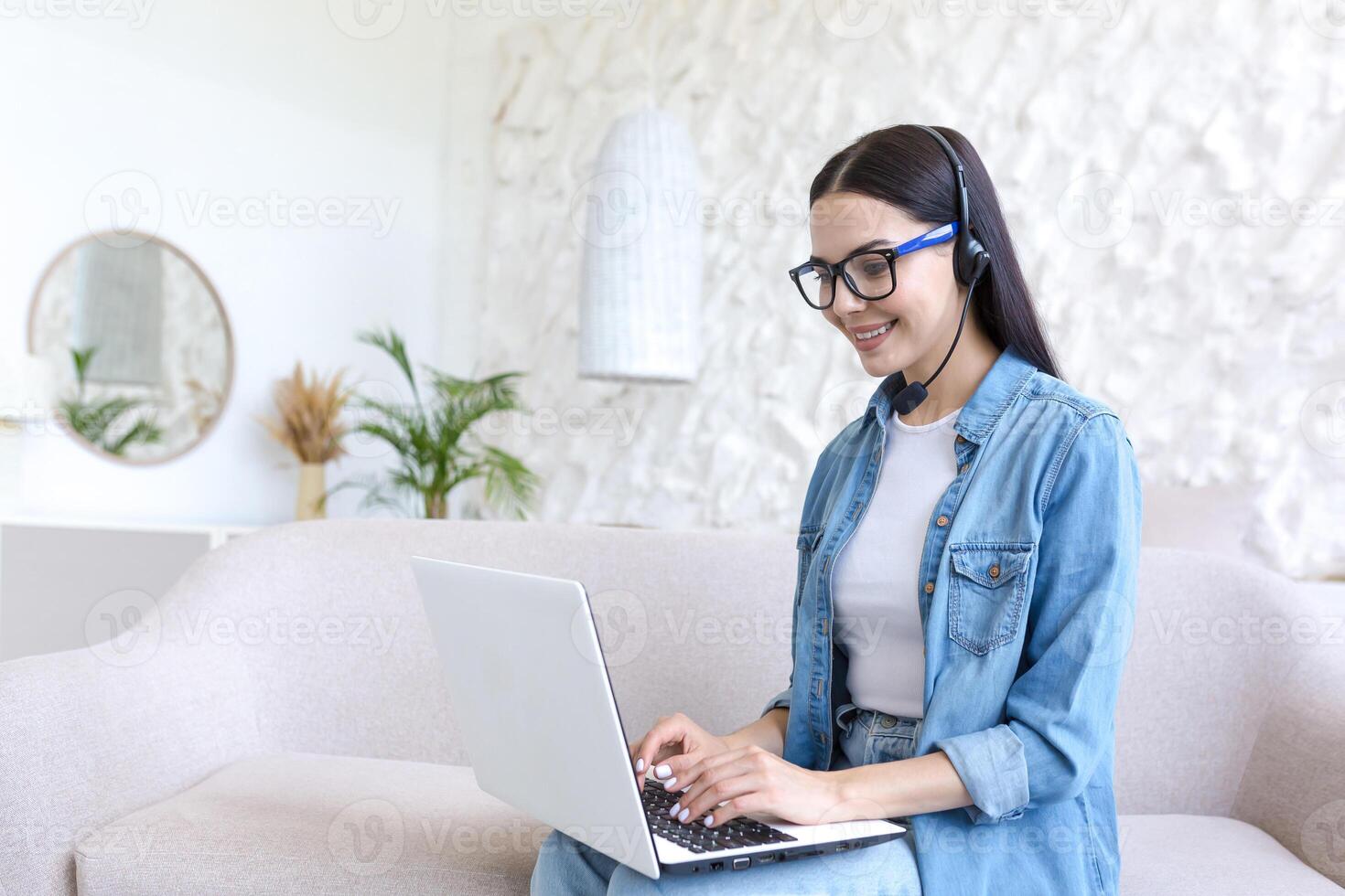 Young beautiful woman working at home sitting on sofa, using 