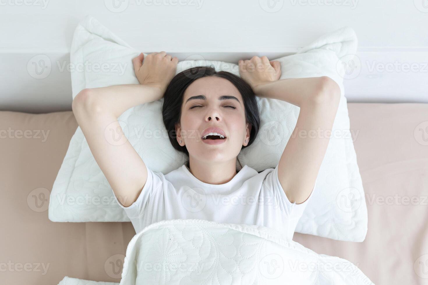 A beautiful woman lies in bed, enjoys an orgasm, alone at home. photo