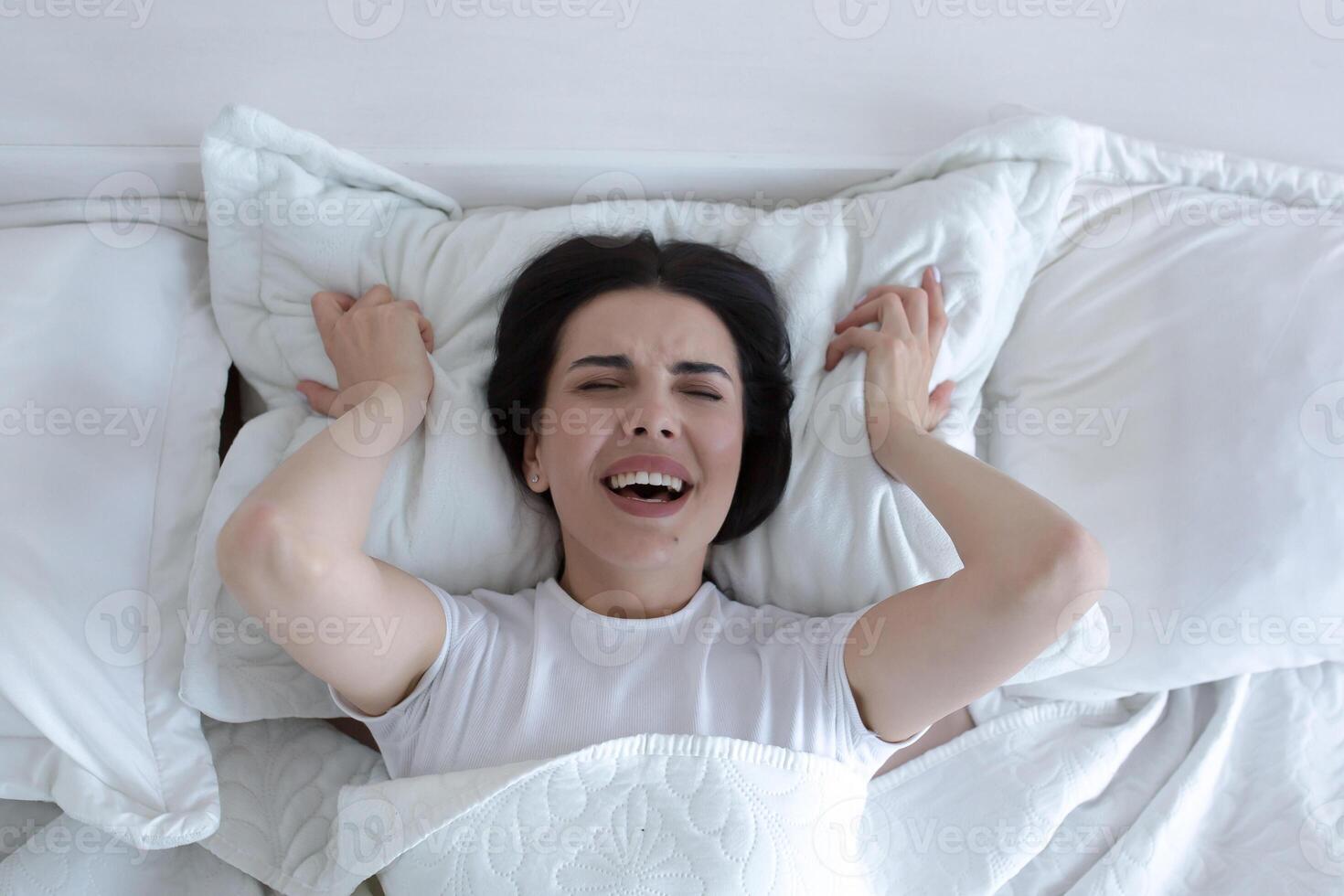 Top view, depressed woman lying in bed crying and screaming with sadness. photo