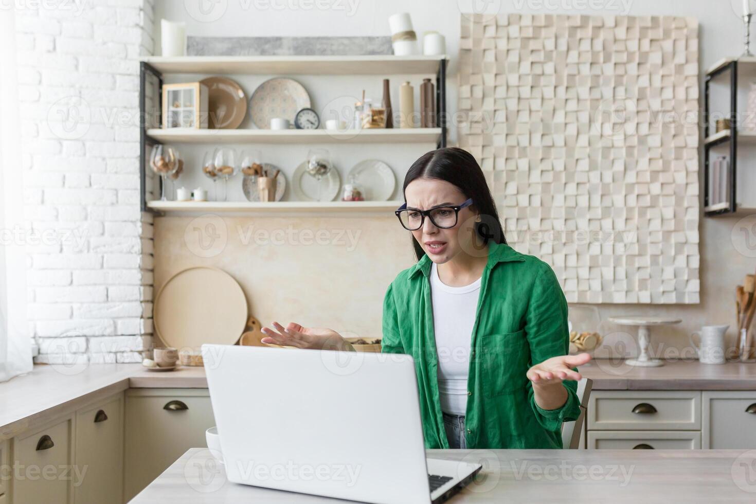 Upset young businesswoman, freelancer works from home He is sitting at the table at home, there is no Internet, the laptop is broken. He spreads his hands angrily. photo