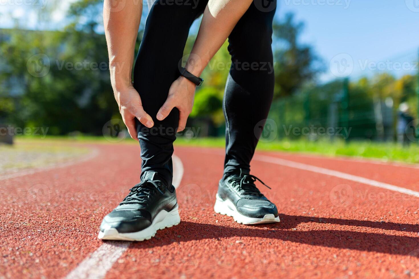 Sports injury, close-up photo of male runner's legs, athlete injured himself while running in stadium, during fitness class, massages leg muscles.