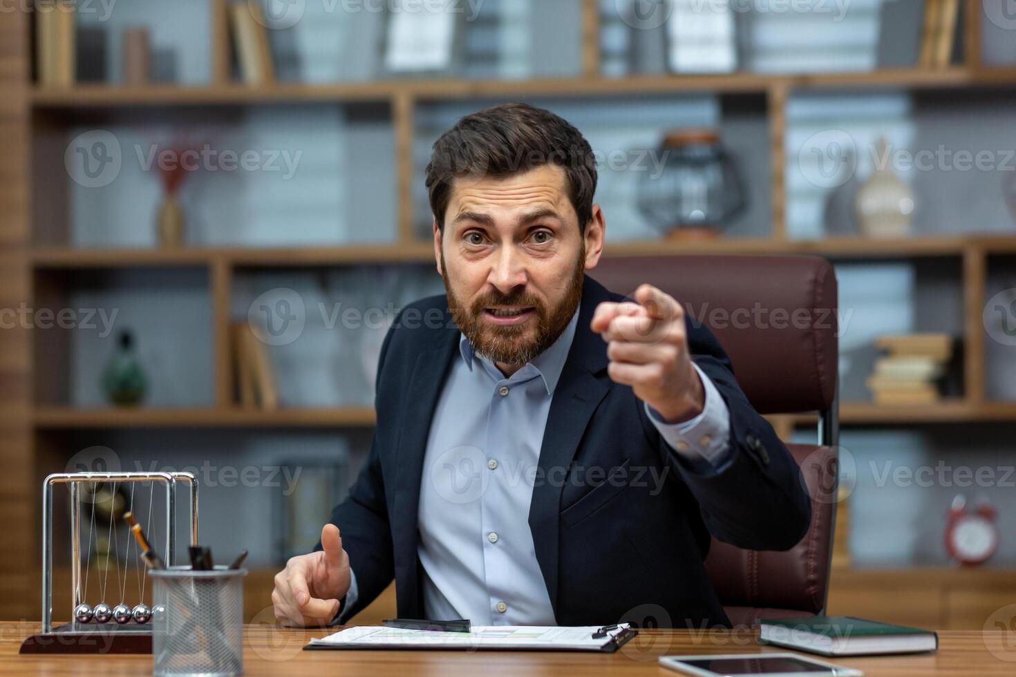 Portrait of an angry young businessman talking on a call in the office with clients, team, partners. Unsatisfied with work, burning deadlines, firing from a job photo