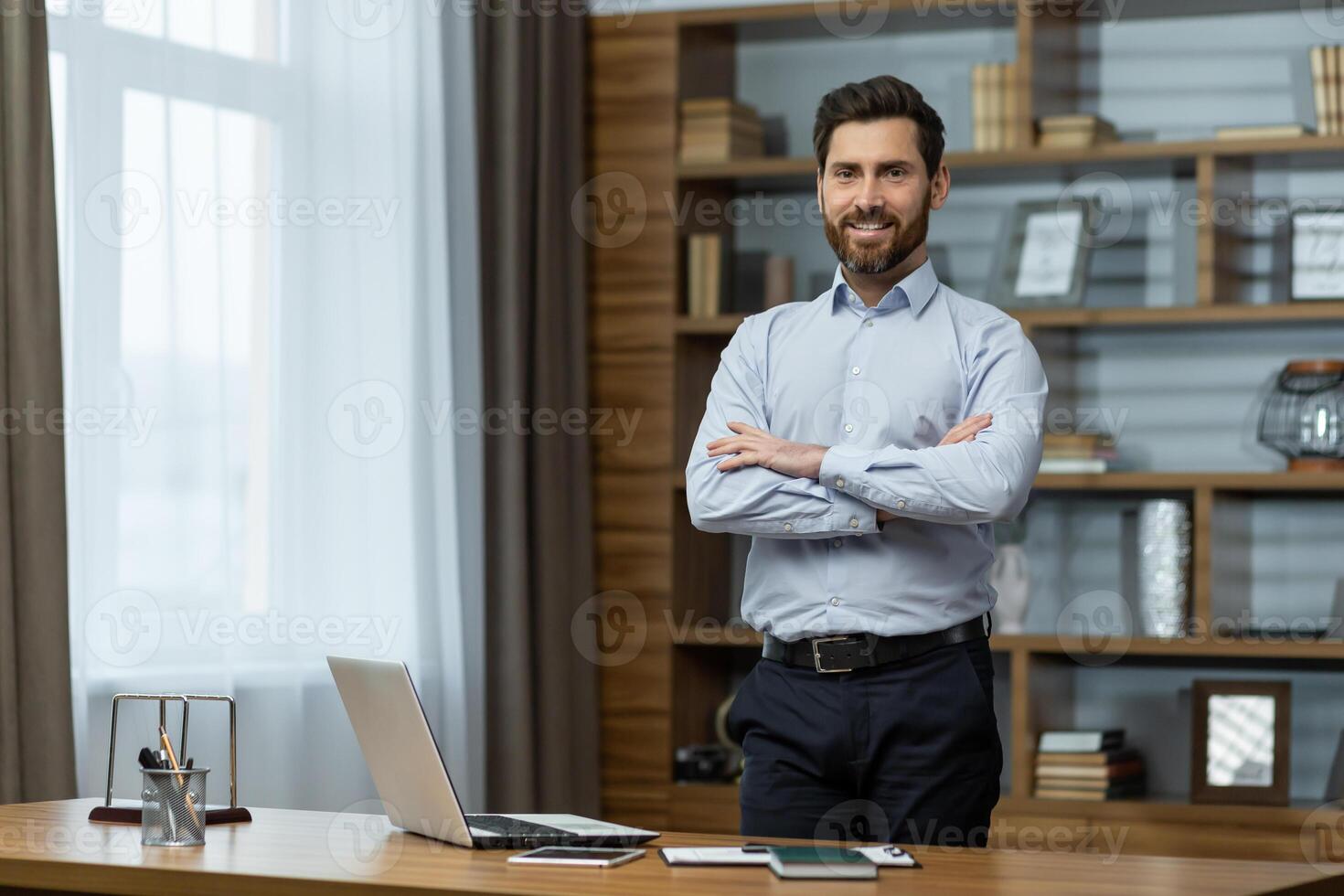 Portrait of successful businessman in office, man in shirt smiling and looking at camera, mature boss with beard with shaggy hands standing at workplace inside building. photo