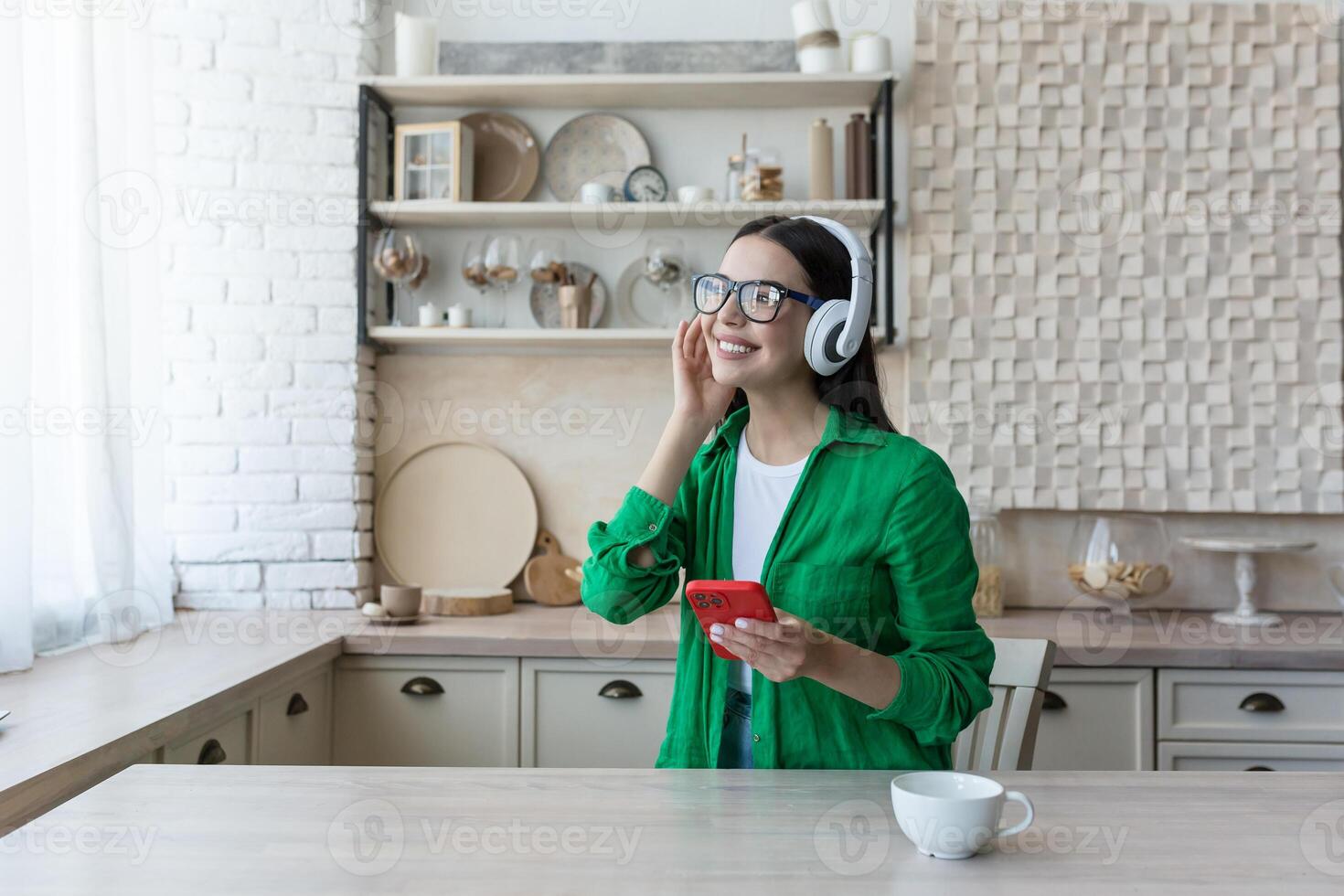 A young beautiful female student is studying in headphones, studying at home online from the phone, listening to a podcast, a lecture. photo