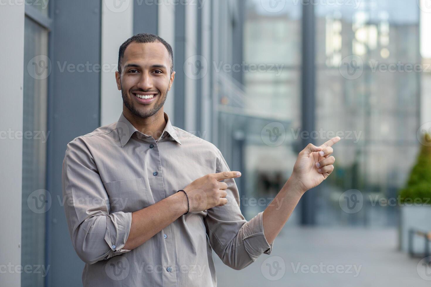 African American businessman smiling and pointing, strolling outside a modern office building reflecting professionalism. photo