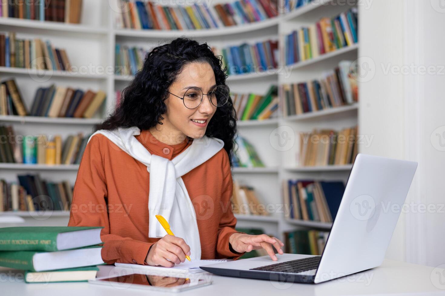 A cheerful African American woman with curly hair, using her smartphone and a credit card for online shopping. She is smiling, standing in a bright, modern environment. photo