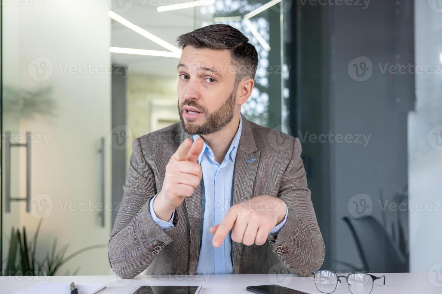 Professional male executive points and explains concepts during a corporate meeting in a modern office setting. photo