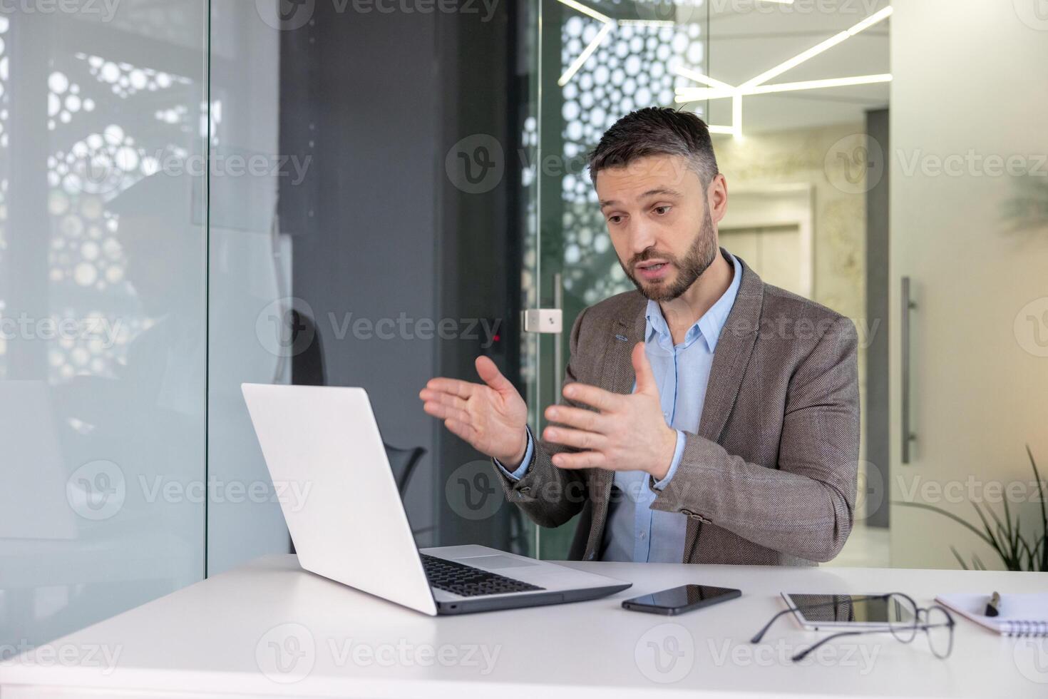 Confident male professional using laptop to explain concepts in a contemporary office environment, illustrating effective communication. photo