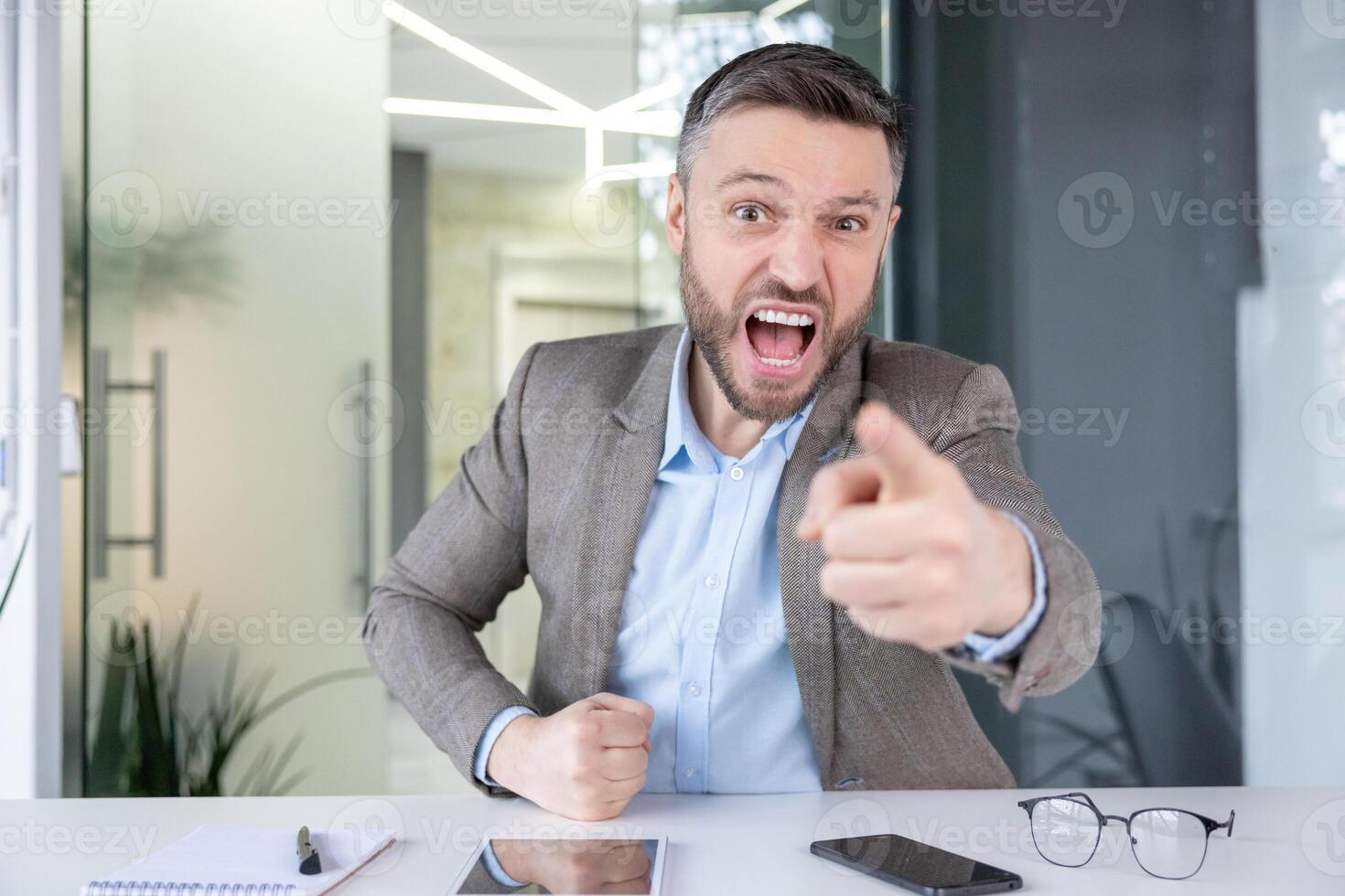 An upset businessman is expressing anger and frustration while looking into the camera, possibly during a call. photo