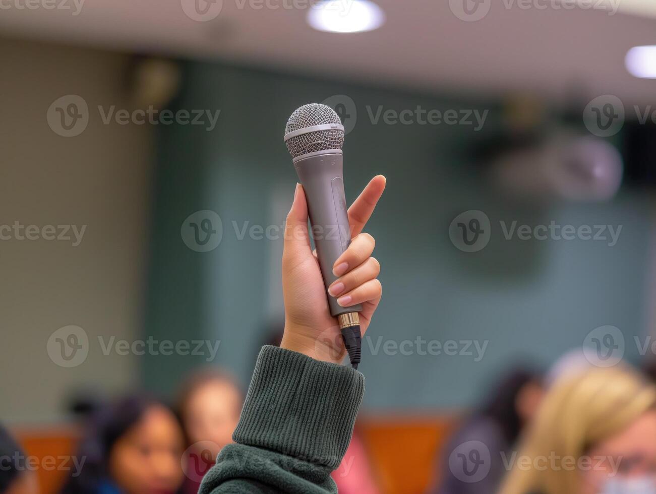 A hand holding up a microphone in a professional setting, symbolizing the power of speech and communication. photo