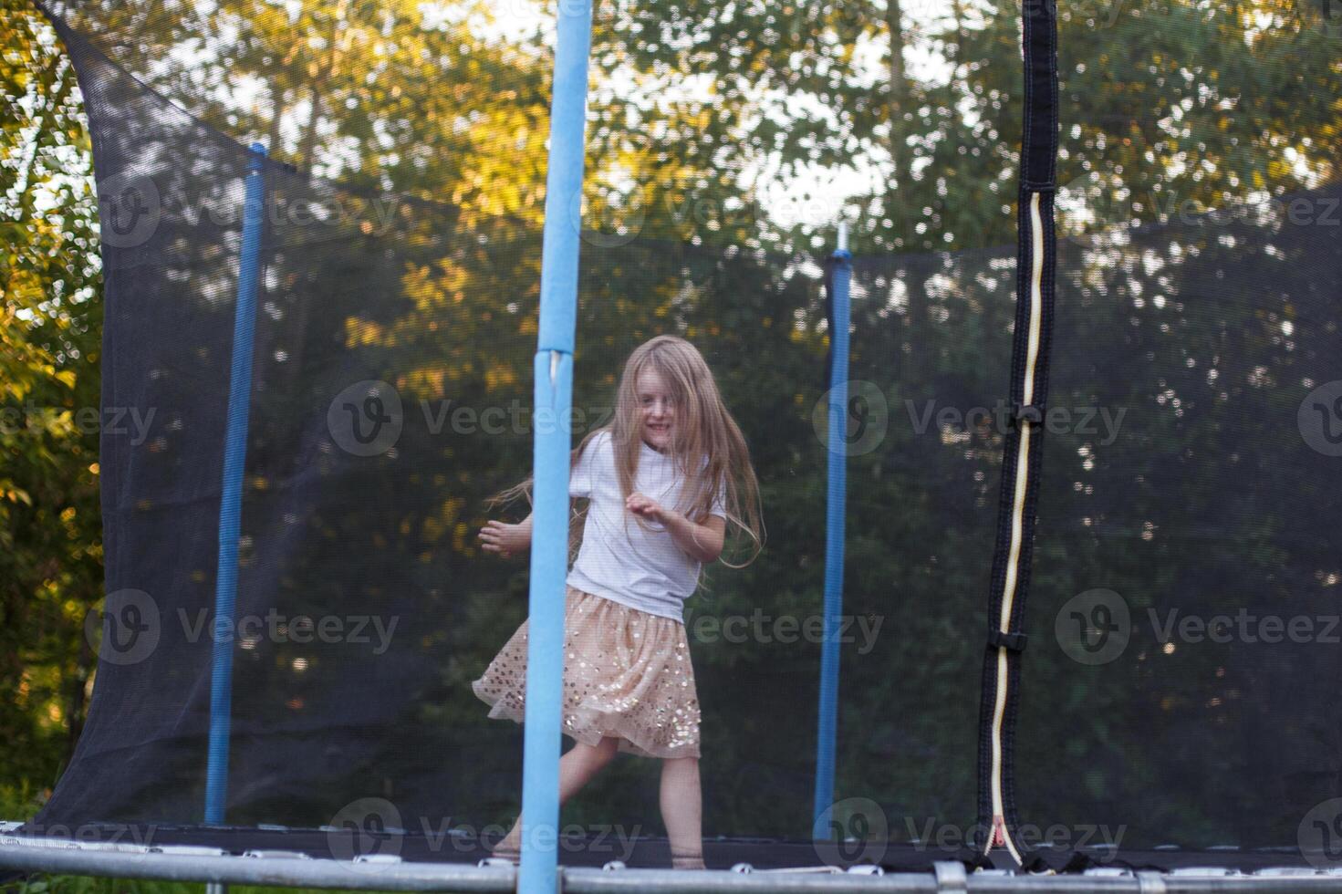 Little child girl jumping on the trampoline in the back yard photo