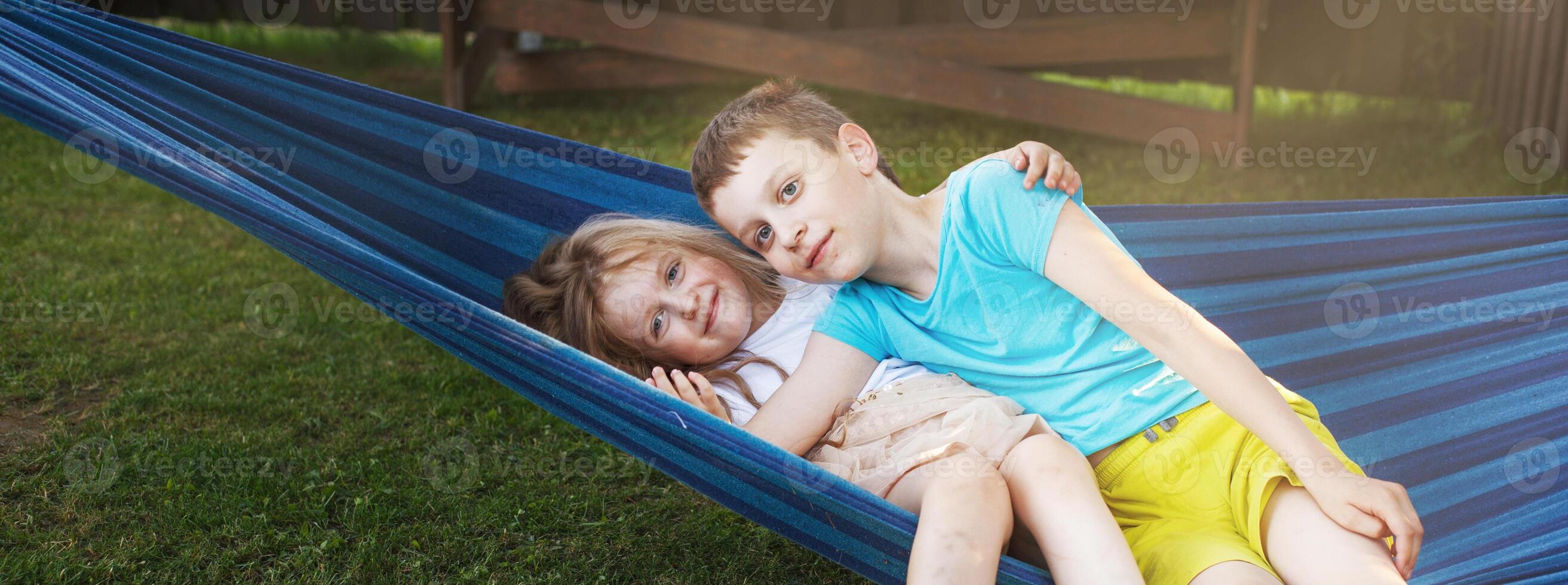 children brother and sister resting in the garden on a hammock photo