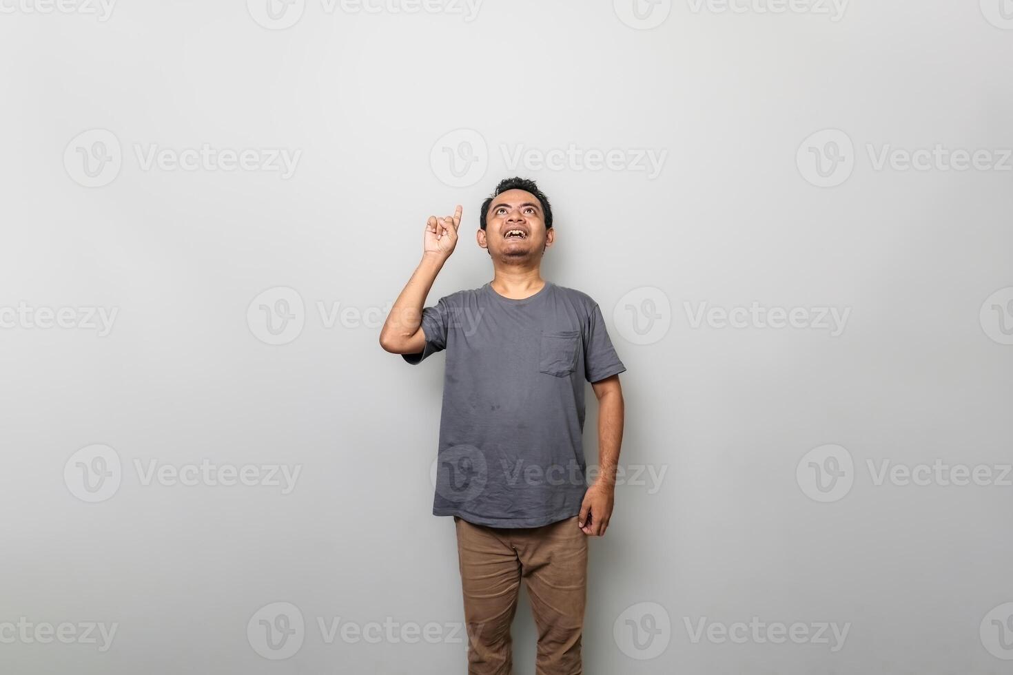 an asian man in gray is getting an idea while looking and pointing upwards isolated on white background photo
